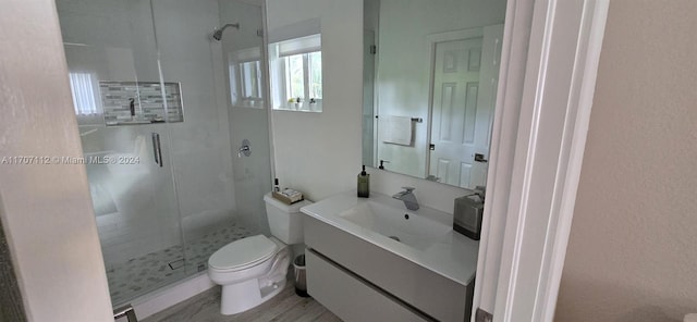 bathroom featuring vanity, hardwood / wood-style flooring, toilet, and a shower with door