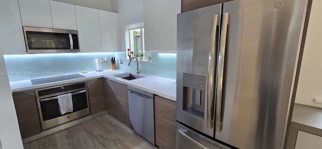 kitchen featuring sink, white cabinets, stainless steel appliances, and light hardwood / wood-style floors