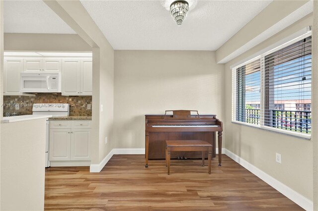 living room with a textured ceiling, wood-type flooring, and ceiling fan with notable chandelier