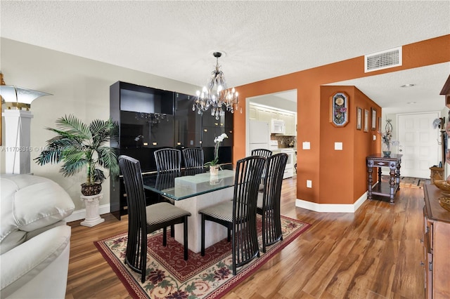 dining area with a chandelier, hardwood / wood-style floors, and a textured ceiling