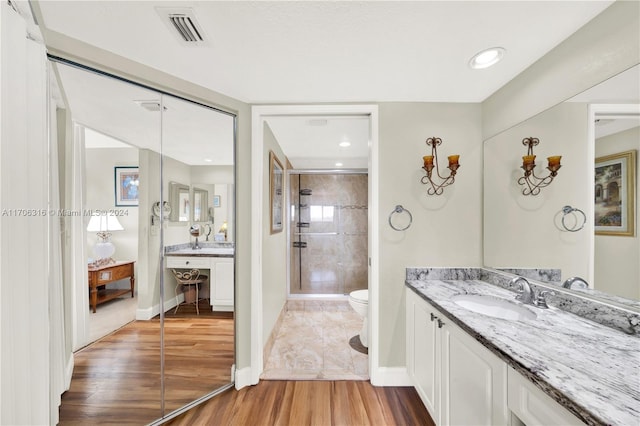 bathroom with hardwood / wood-style floors, vanity, toilet, and a shower with door