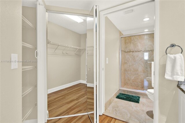 bathroom with toilet and a shower with shower door