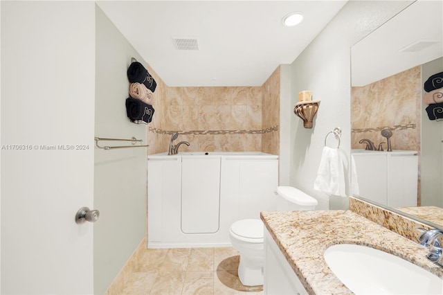 bathroom with a bathtub, vanity, and toilet