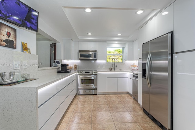 kitchen featuring backsplash, stainless steel appliances, white cabinetry, and sink