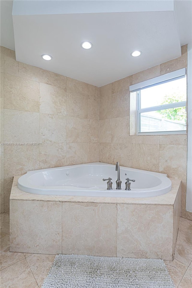 bathroom with a relaxing tiled tub, tile patterned floors, and tile walls