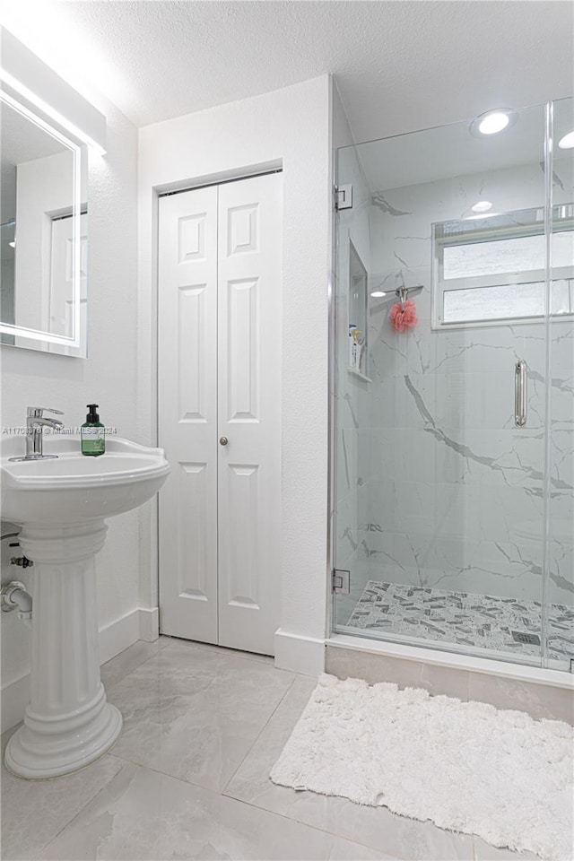 bathroom featuring a shower with shower door and a textured ceiling