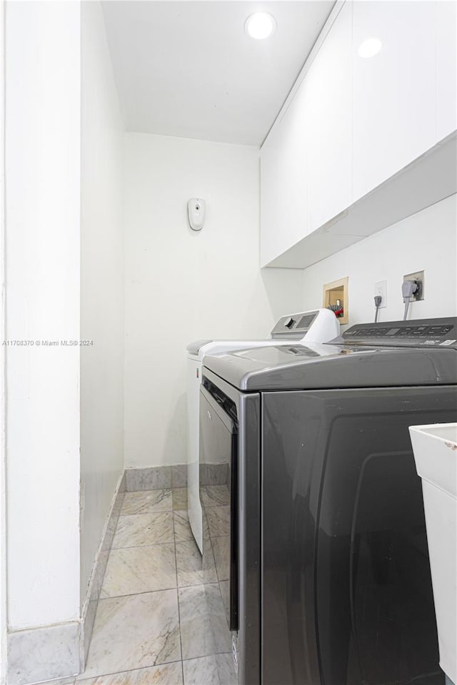 washroom featuring cabinets, independent washer and dryer, and sink