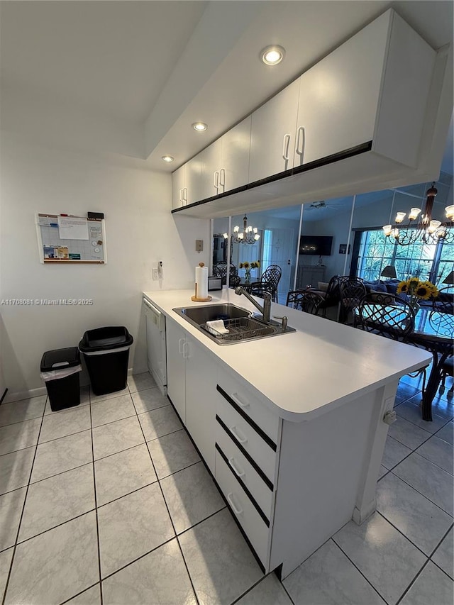 kitchen with dishwasher, sink, light tile patterned floors, kitchen peninsula, and a chandelier