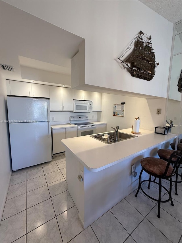 kitchen with a kitchen breakfast bar, sink, white appliances, and kitchen peninsula