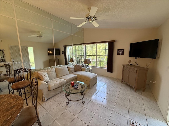 living room featuring a textured ceiling, ceiling fan, light tile patterned flooring, and lofted ceiling