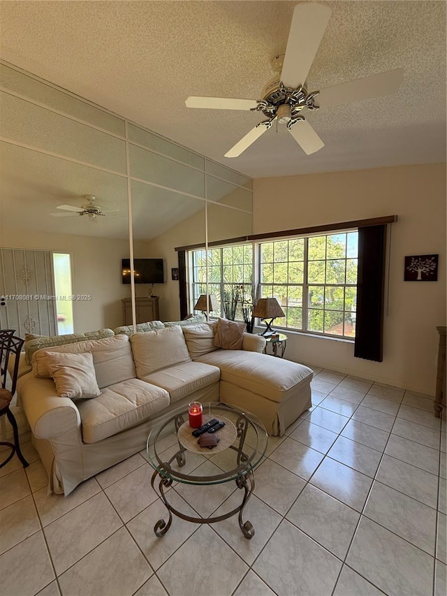 living room with ceiling fan, light tile patterned floors, a textured ceiling, and vaulted ceiling