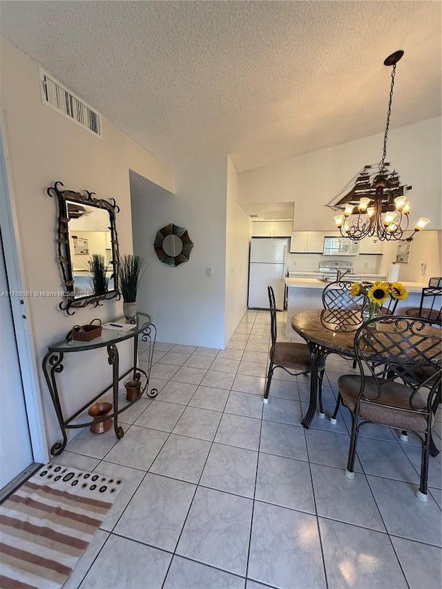 dining space featuring a chandelier, light tile patterned floors, and a textured ceiling