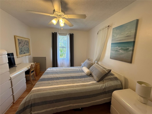 bedroom with hardwood / wood-style flooring, ceiling fan, and a textured ceiling