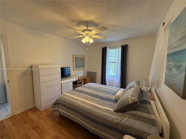 bedroom with ceiling fan, light hardwood / wood-style floors, and a textured ceiling