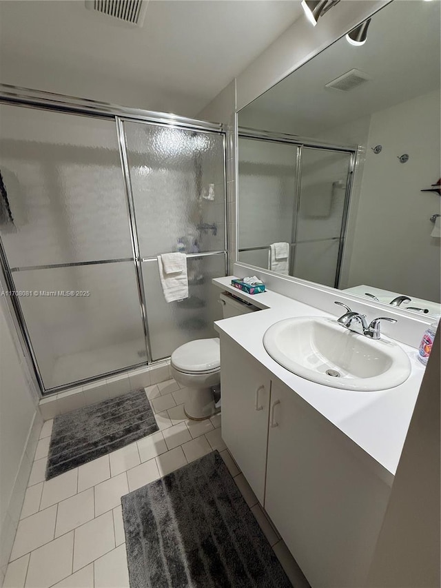 bathroom with tile patterned flooring, vanity, a shower with door, and toilet