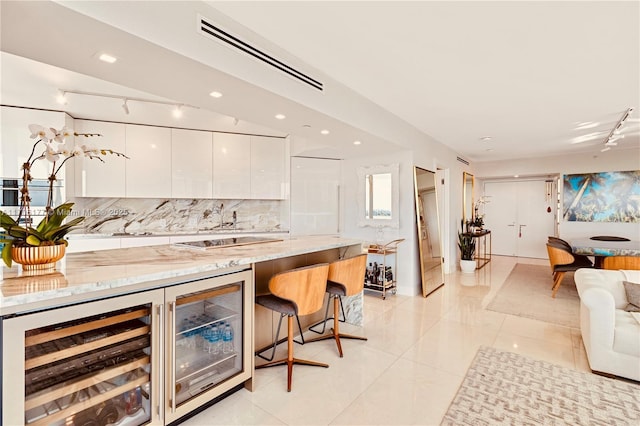 bar featuring light tile patterned floors, beverage cooler, visible vents, and decorative backsplash