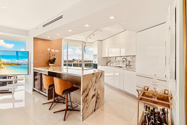 kitchen featuring a center island, beverage cooler, white cabinetry, and modern cabinets