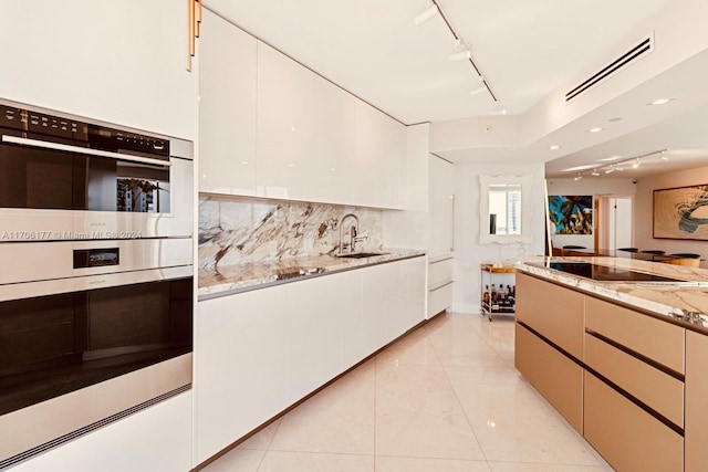 kitchen with white cabinets, black electric cooktop, light stone countertops, and sink