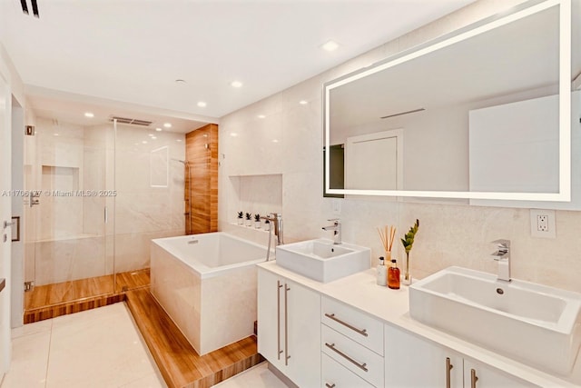 full bathroom featuring a stall shower, a sink, tile walls, and a bath