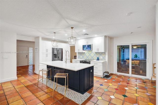 kitchen featuring appliances with stainless steel finishes, a kitchen island with sink, sink, pendant lighting, and white cabinetry