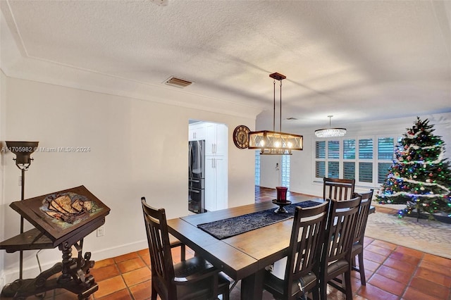 dining area with a textured ceiling, tile patterned floors, and a notable chandelier