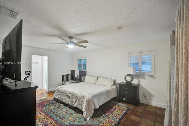 bedroom with dark tile patterned flooring, ceiling fan, and a textured ceiling