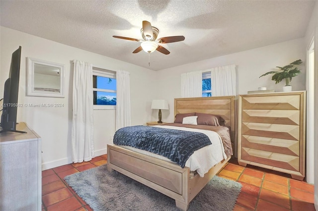 bedroom with tile patterned flooring, ceiling fan, and a textured ceiling