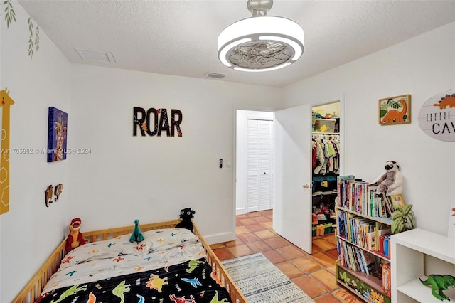 bedroom with a spacious closet, a closet, light tile patterned flooring, and a textured ceiling