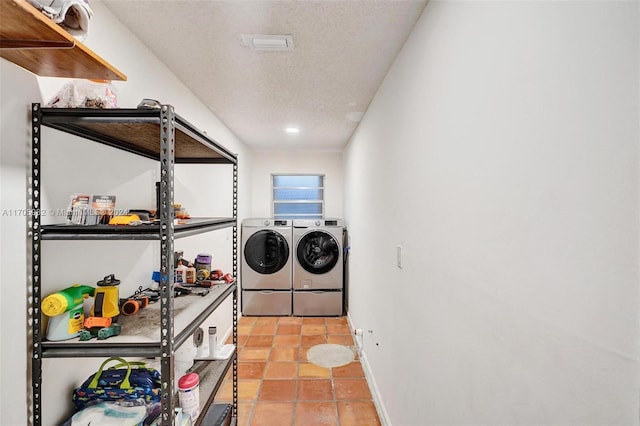 laundry room featuring washer and clothes dryer, light tile patterned floors, and a textured ceiling