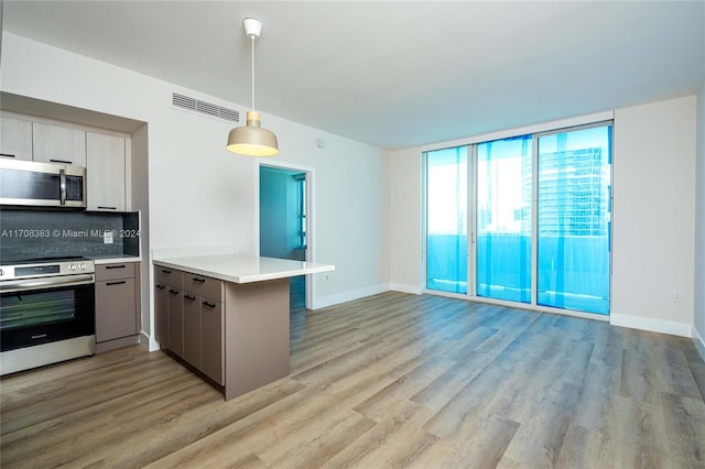 kitchen featuring kitchen peninsula, stove, tasteful backsplash, pendant lighting, and light hardwood / wood-style floors