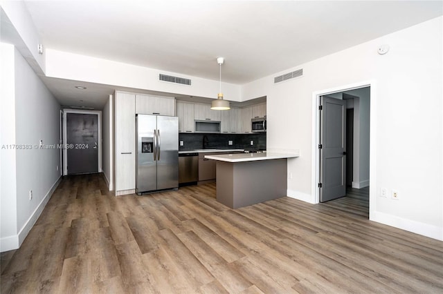 kitchen with gray cabinetry, sink, hanging light fixtures, stainless steel appliances, and hardwood / wood-style floors