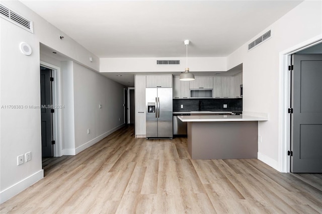 kitchen with kitchen peninsula, stainless steel fridge, gray cabinetry, and light hardwood / wood-style floors