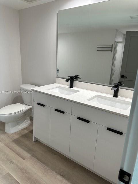 bathroom featuring vanity, hardwood / wood-style flooring, toilet, and a shower with shower door