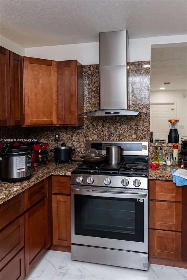 kitchen featuring decorative backsplash, wall chimney exhaust hood, dark stone counters, and stainless steel gas range