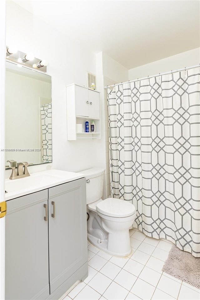 bathroom featuring tile patterned flooring, vanity, toilet, and walk in shower