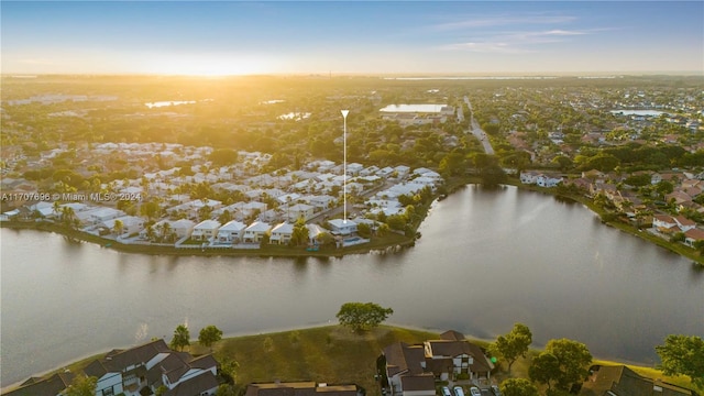 aerial view at dusk featuring a water view