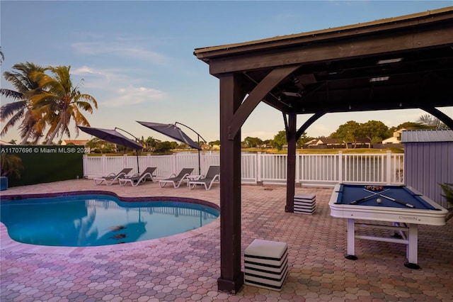 pool at dusk with a gazebo and a patio area