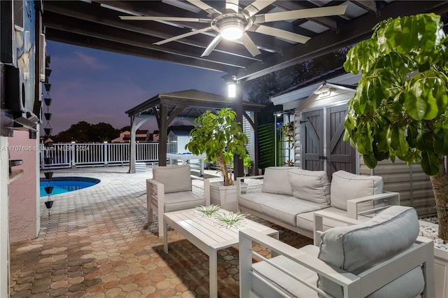 patio terrace at dusk with a fenced in pool, outdoor lounge area, and a storage shed