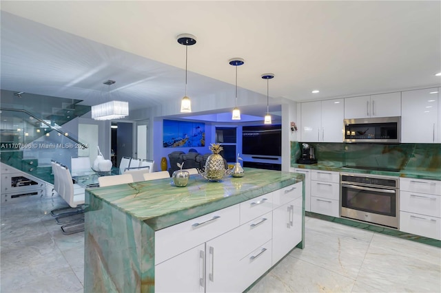 kitchen with white cabinets, decorative backsplash, stainless steel appliances, and hanging light fixtures