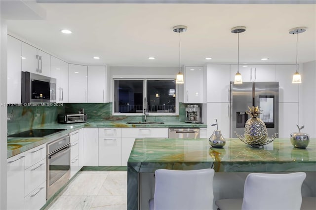 kitchen featuring white cabinets, appliances with stainless steel finishes, and hanging light fixtures