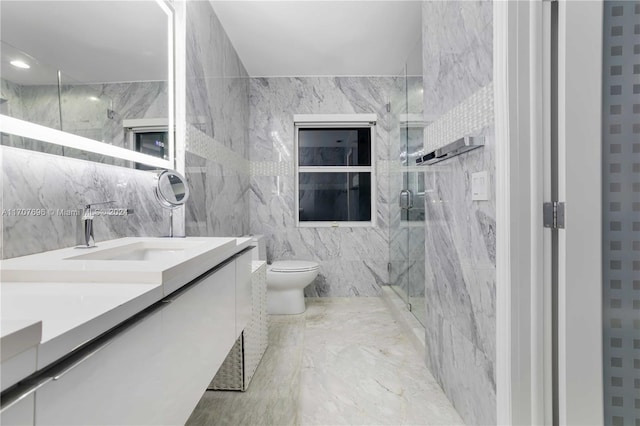 bathroom featuring vanity, toilet, a shower with shower door, and tile walls