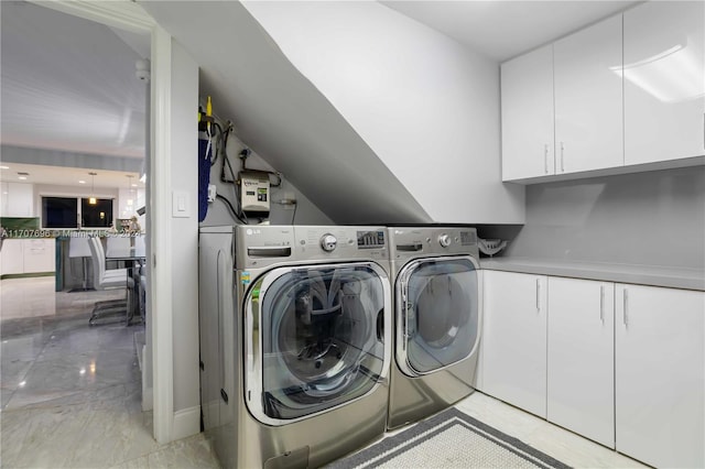 clothes washing area with cabinets and separate washer and dryer