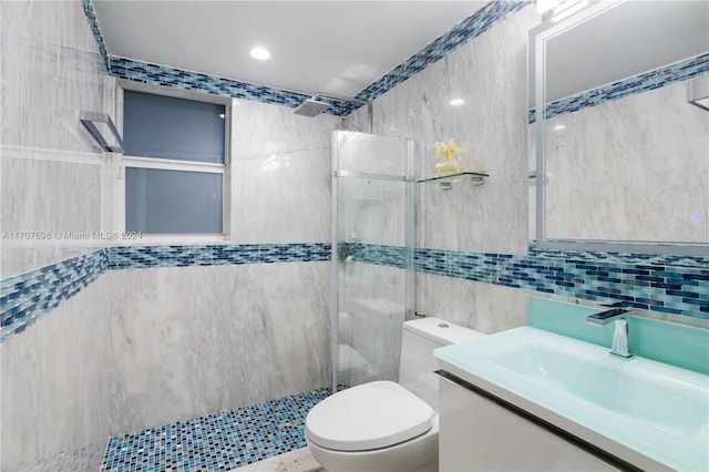 bathroom featuring vanity, toilet, tile walls, and a tile shower