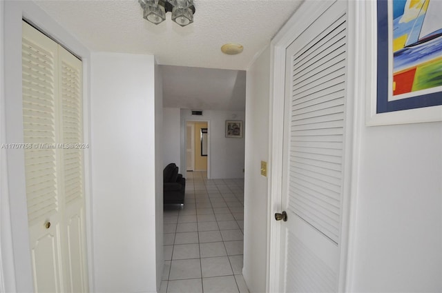 corridor with light tile patterned floors and a textured ceiling