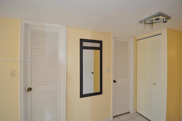 corridor with light tile patterned floors and a textured ceiling