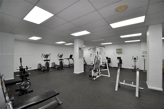 gym featuring a wall mounted air conditioner and a paneled ceiling