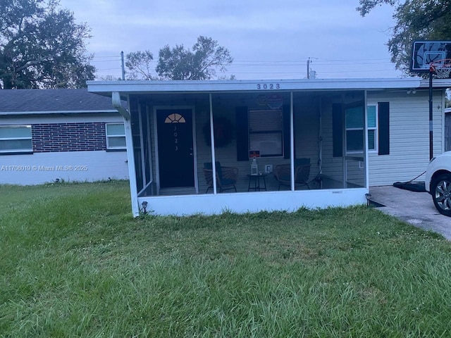 rear view of house featuring a yard and a sunroom