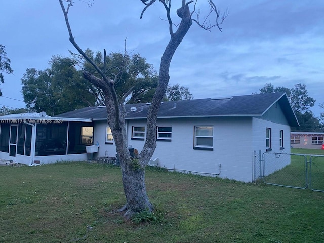 back of property featuring a sunroom and a lawn