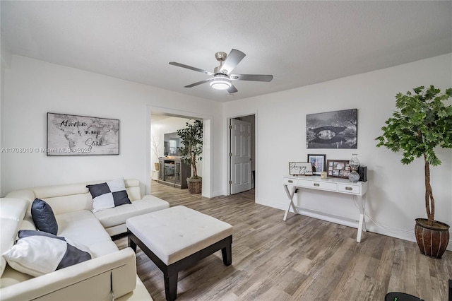 living room featuring a textured ceiling, wood-type flooring, and ceiling fan