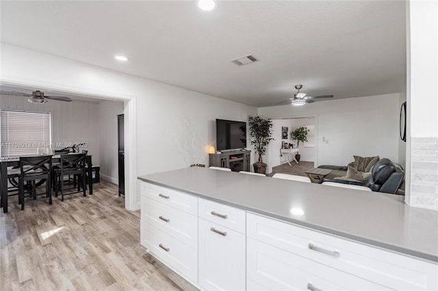 kitchen with white cabinetry, ceiling fan, kitchen peninsula, and light hardwood / wood-style flooring